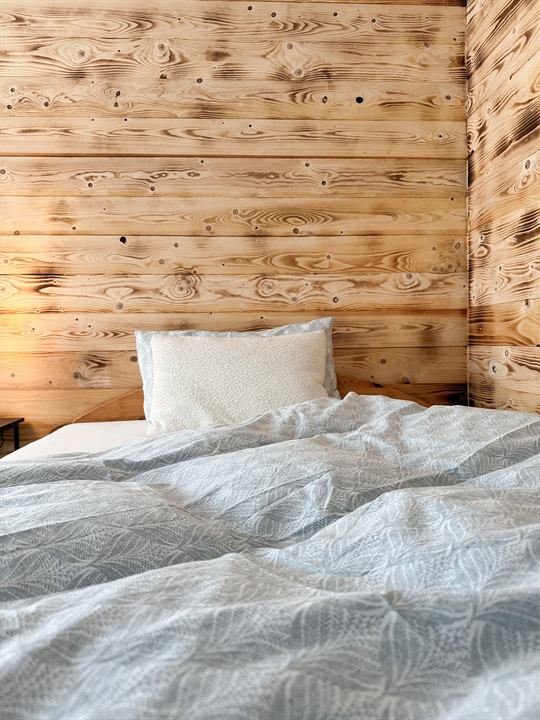 Schlafzimmer mit Holzwand und Bett