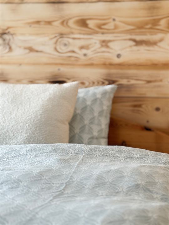 Bett mit Kissen vor der Holzwand