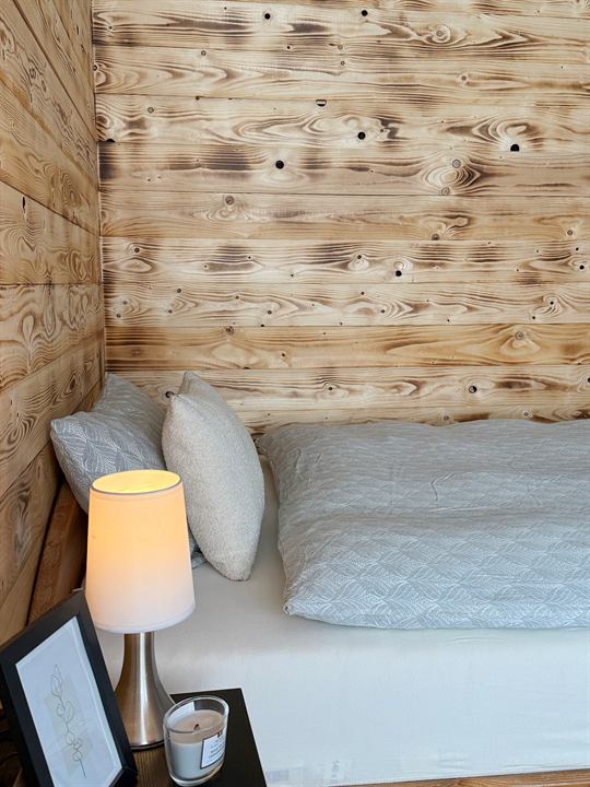 Bett in der Holzecke mit Nachttischlampe