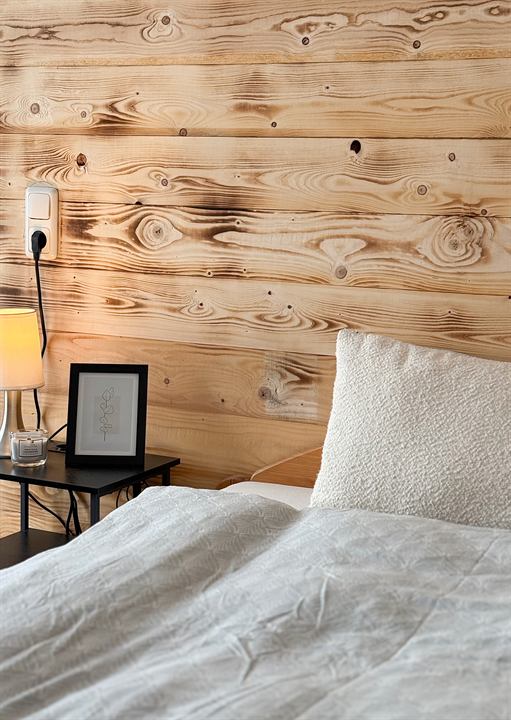 Bett vor der Holzwand mit Bilderrahmen