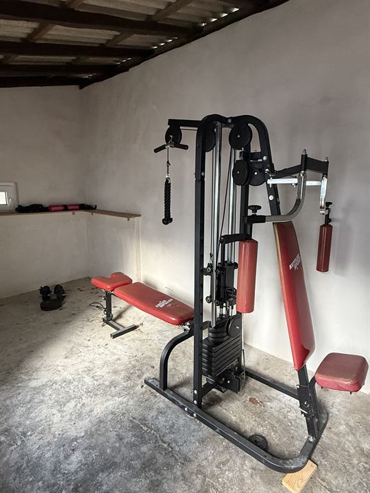 Fitnessraum mit Kraftstation, Hantelbank und Kurzhanteln