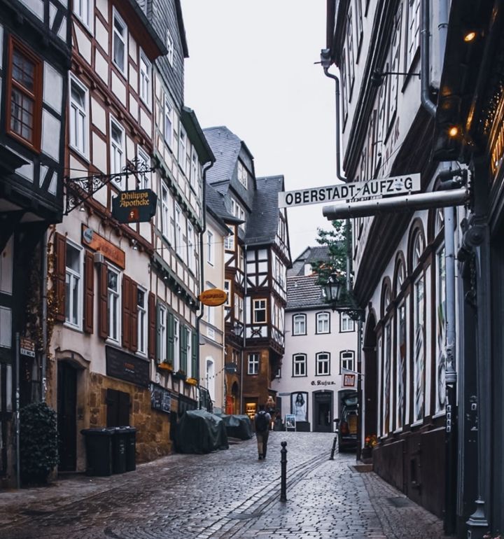 Gasse der Marburger Oberstadt mit Fachwerkhäusern und Kopfsteinpflaster, über der Straße ein Schild Oberstadt-Aufzug